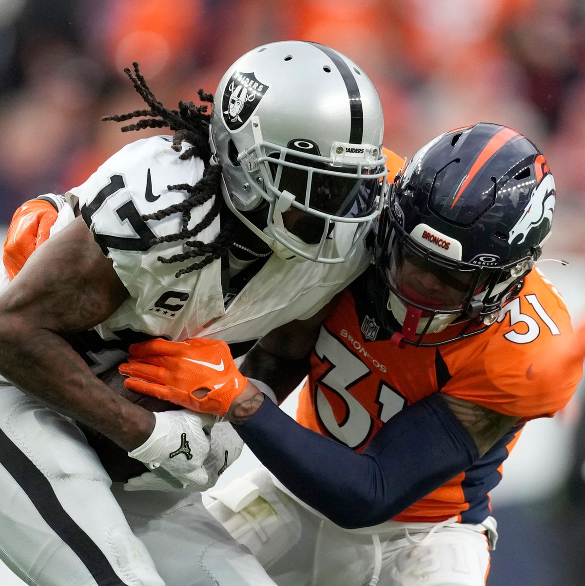Davante Adams (17), Wide Receiver der Las Vegas Raiders, wird in der zweiten Hälfte von Justin Simmons (31), Safety der Denver Broncos, angegriffen. - Foto: David Zalubowski/AP/dpa