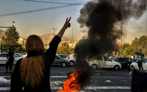 Eine Frau steht wÀhrend einer Demonstration in Teheran vor einem brennenden Autoreifen und zeigt das Victory-Zeichen. - Foto: Uncredited/AP/dpa Eine Frau steht wÀhrend einer Demonstration in Teheran vor einem brennenden Autoreifen und zeigt das Victory-Zeichen. - Foto: Uncredited/AP/dpa