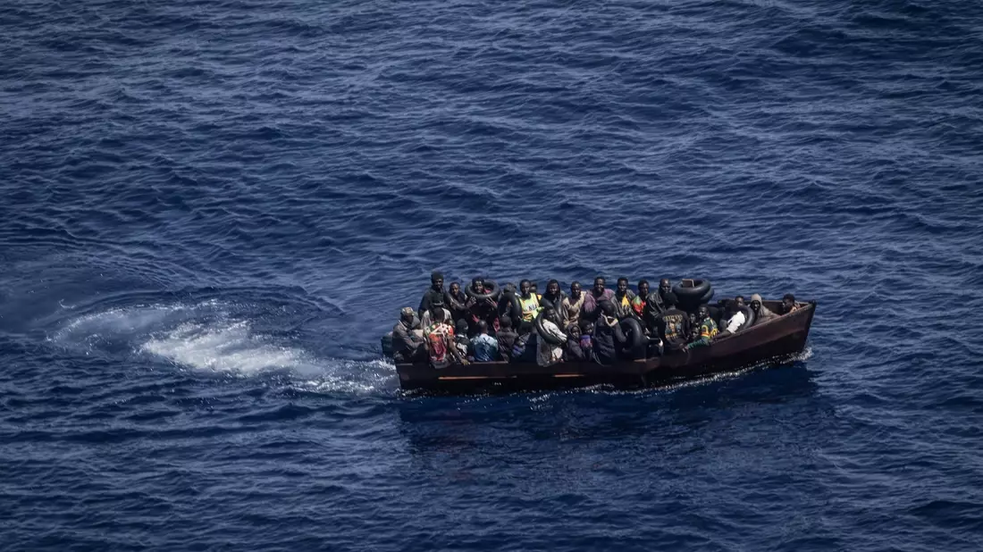 Migranten steuern ein Boot in Richtung der Insel Lampedusa. - Bild: Oliver Weiken/dpa