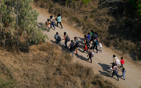 Migranten gehen im Süden von Texas über einen Feldweg, nachdem sie die Grenze zwischen den USA und Mexiko überquert haben. - Foto: Julio Cortez/AP/dpa