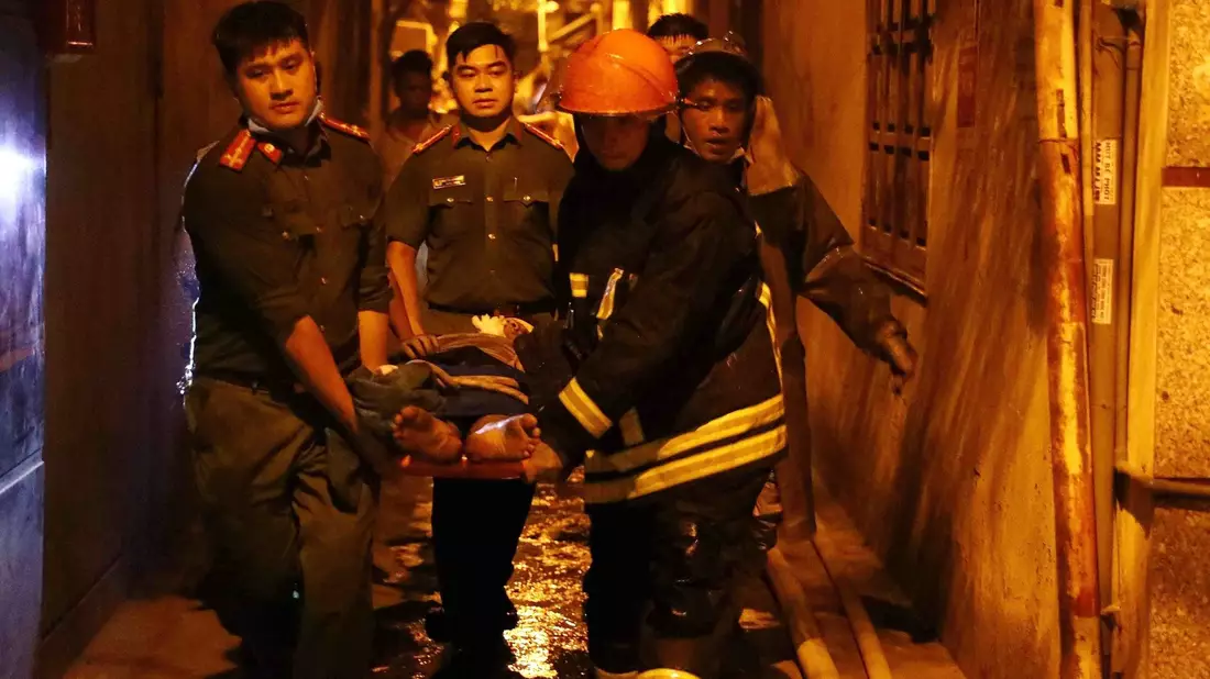 Rettungskräfte tragen eine Person aus einem brennenden Gebäude in der vietnamesischen Hauptstadt Hanoi. - Bild: Pham Trung Kien/VNA/AP/dpa