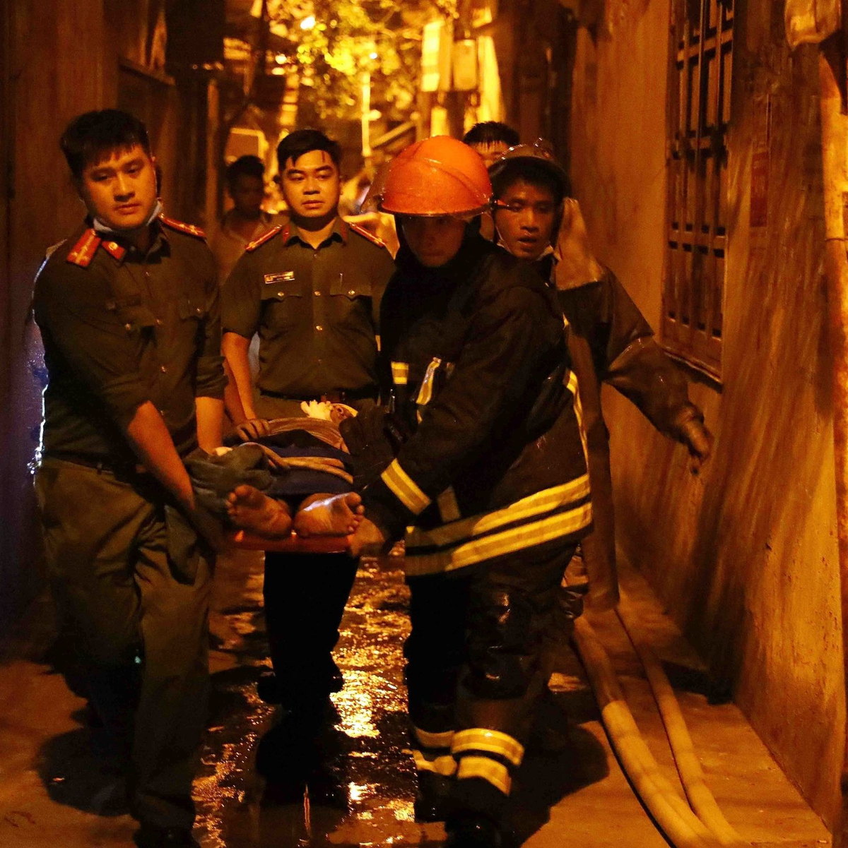 Rettungskräfte tragen eine Person aus dem brennenden Gebäude in Hanoi. - Foto: Pham Trung Kien/VNA/AP/dpa
