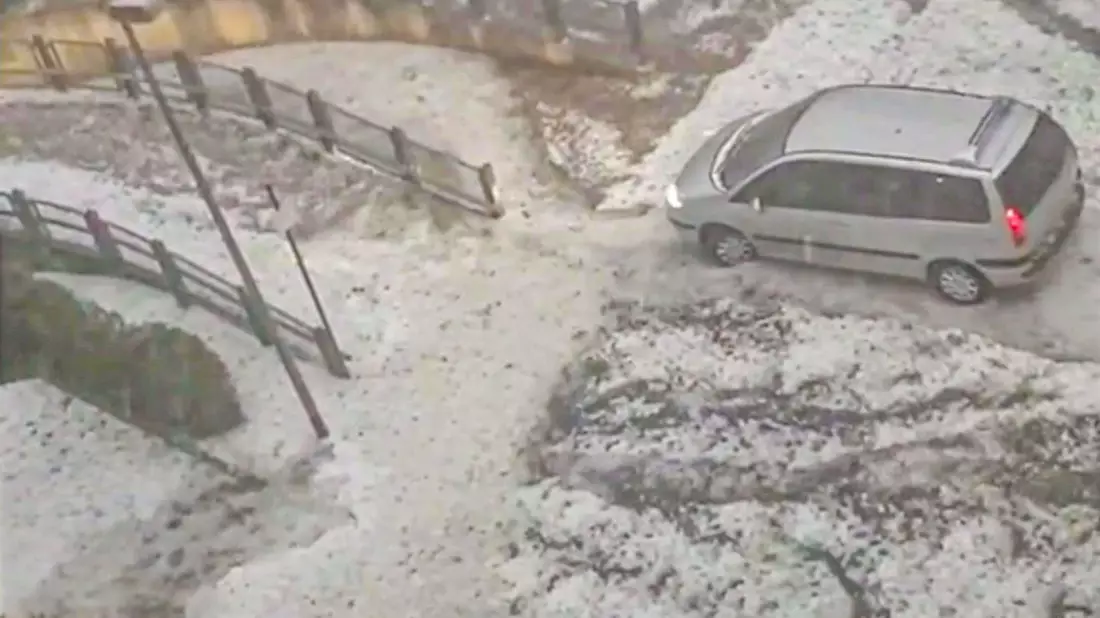 Ein Van fährt nach einem heftigen Hagelschauer über einen winterlich anmutenden Parkplatz in Worms. - Bild: Einsatz-Report24/dpa
