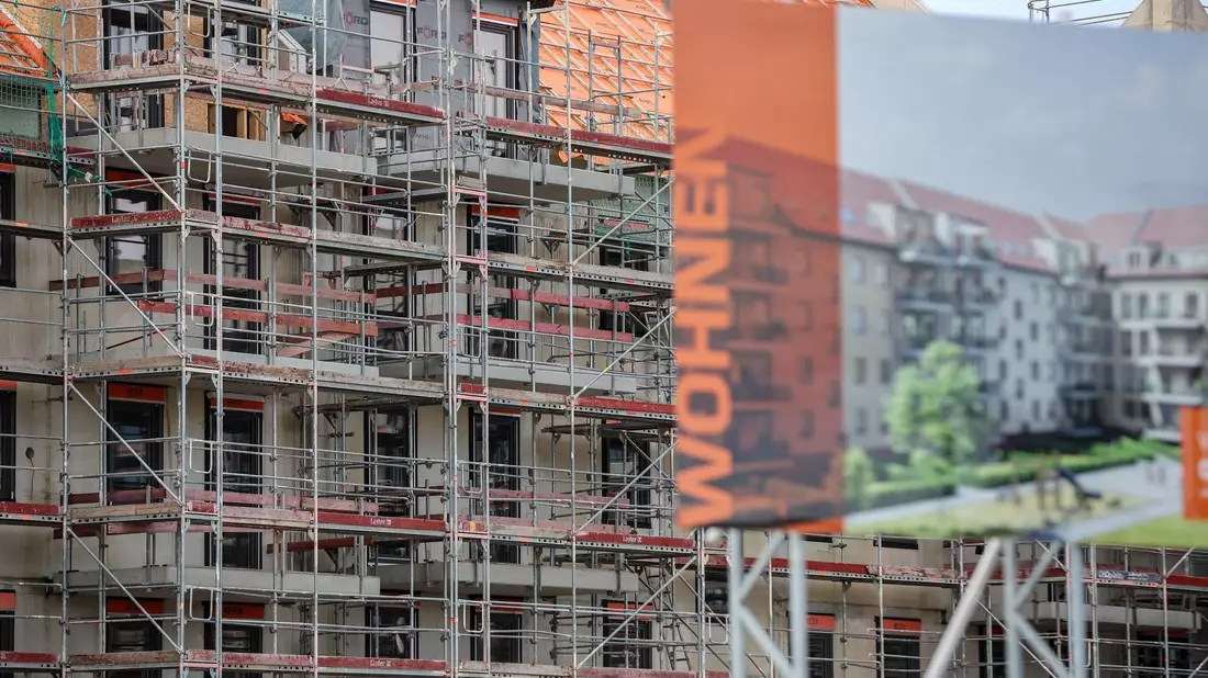 Eine Bautafel steht vor der Baustelle mehrerer Miethäuser in Leipzig. Der Städtetag fordert mehr Wohnungsbau. - Bild: Jan Woitas/dpa