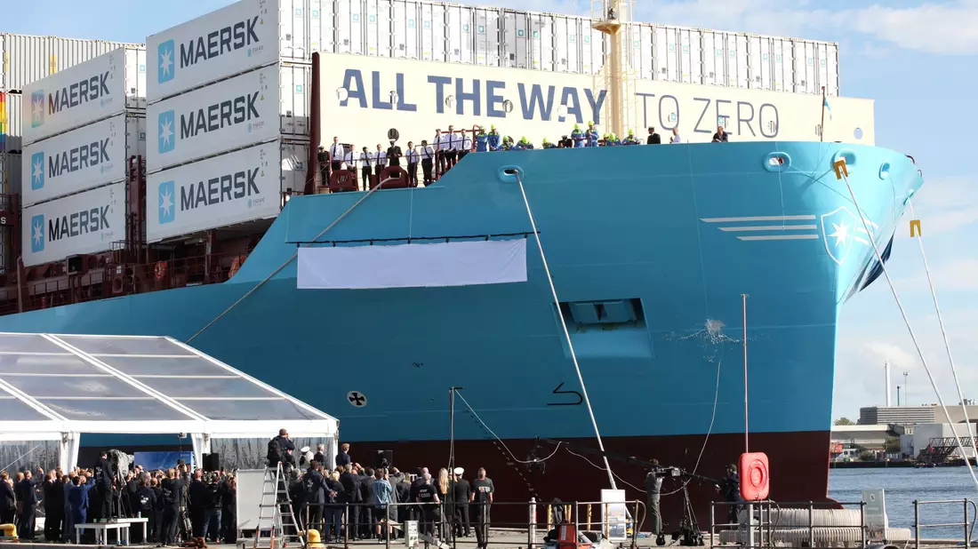 Eine Champagnerflasche zerschellt am Rumpf des weltweit ersten mit grünem Methanol betriebenen Containerschiff. - Bild: Steffen Trumpf/dpa