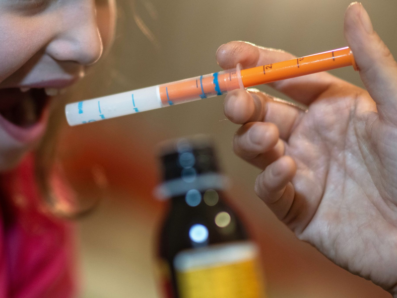 Eine Mutter verabreicht ihrer Tochter eine Dosis Fiebersaft. (Symbolbild) - Foto: Hendrik Schmidt/dpa