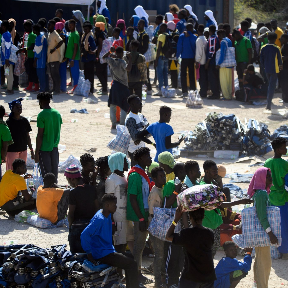 Eine Frau und ein Kind sowie weitere Menschen schlafen im Freien vor dem Erstaufnahmelager auf Lampedusa. - Foto: Valeria Ferraro/AP/dpa