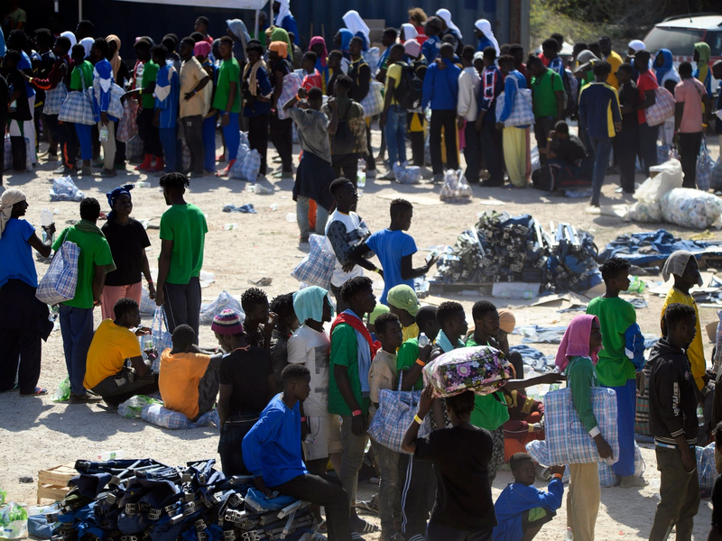 Eine Frau und ein Kind sowie weitere Menschen schlafen im Freien vor dem Erstaufnahmelager auf Lampedusa. - Foto: Valeria Ferraro/AP/dpa