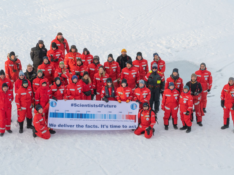 Forscher des Alfred Wegener Instituts mit einem Transparent mit der Aufschrift #Scientists4Future - We deliver the facts. It's time to act in der Arktis. - Foto: Esther Horvath/Alfred Wegener Institut/dpa