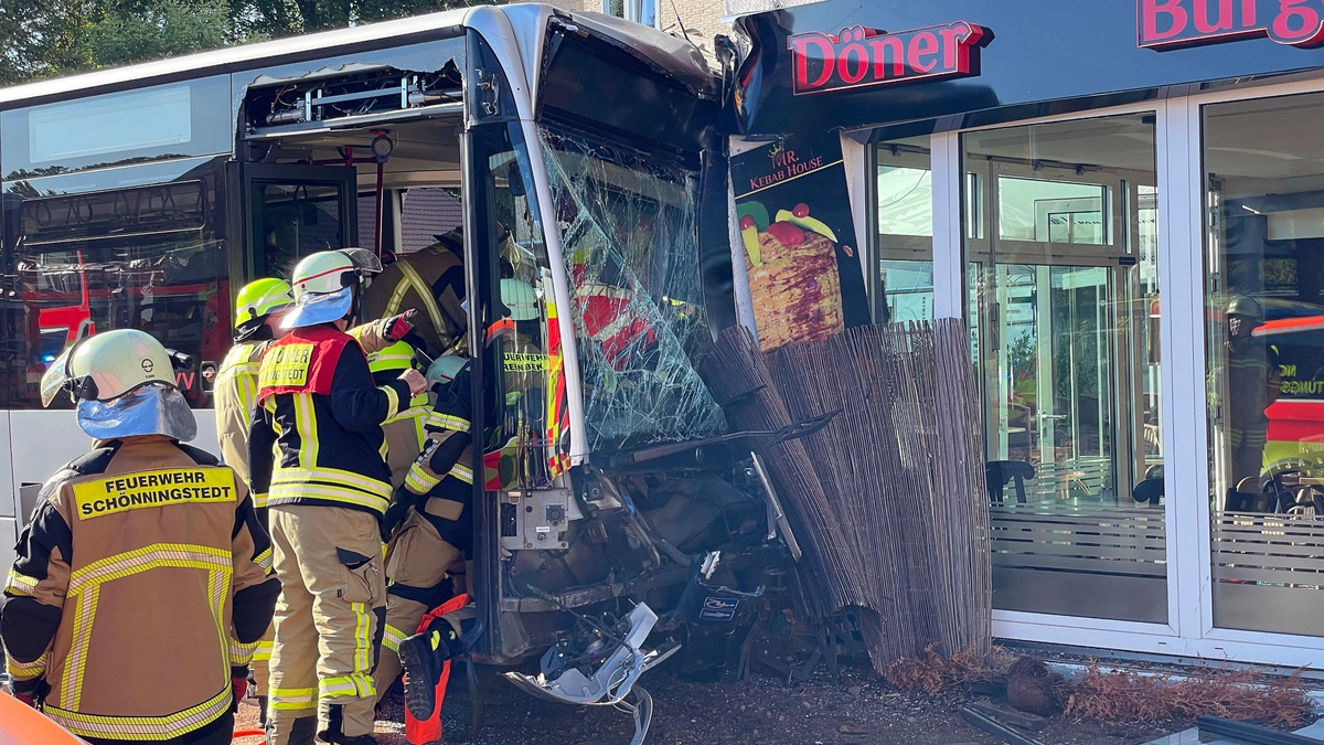Einsatzkräfte der Feuerwehr untersuchen den  Linienbus, der zuvor in einen Dönerladen gekracht war. - Foto: Schröder/NEWS5/dpa