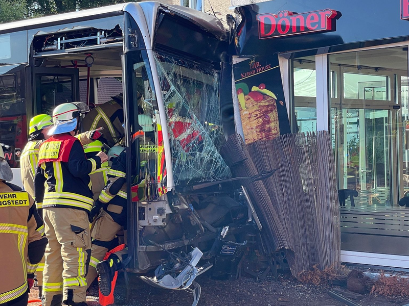 Einsatzkräfte der Feuerwehr untersuchen den  Linienbus, der zuvor in einen Dönerladen gekracht war. - Foto: Schröder/NEWS5/dpa