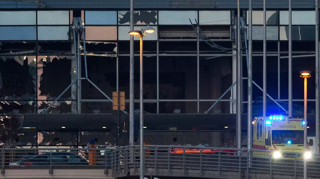Ein Krankenwagen fährt an der zerstörten Fassade des Terminals des Flughafens Zaventem. (Archivbild) - Bild: Peter Dejong/AP/dpa