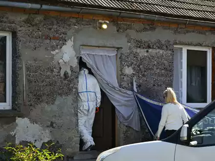Ein Auto der Polizei steht während Ermittlungsarbeiten vor einem Familienhaus. - Foto: Adam Warzawa/PAP/dpa