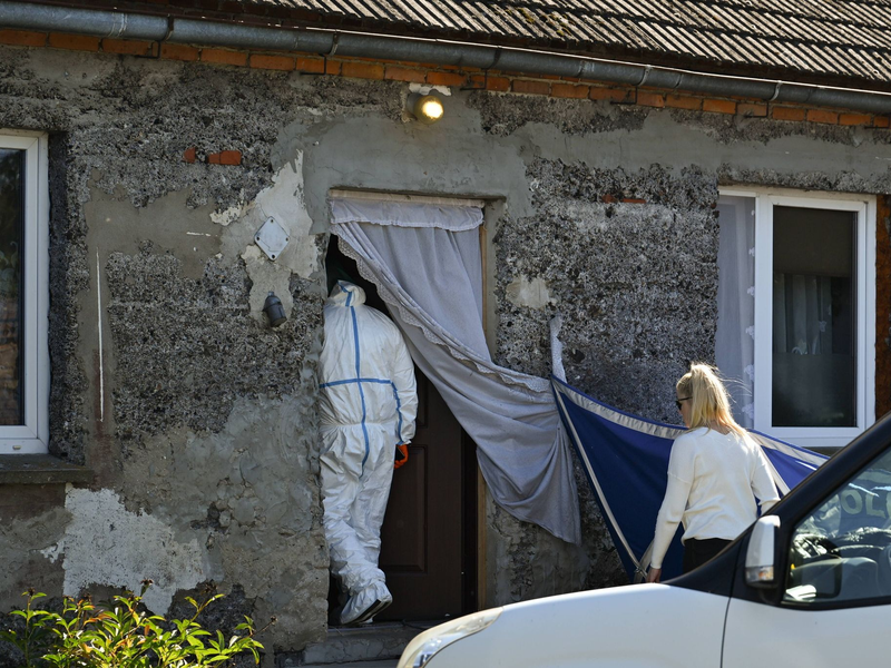 Ein Auto der Polizei steht während Ermittlungsarbeiten vor einem Familienhaus. - Foto: Adam Warzawa/PAP/dpa