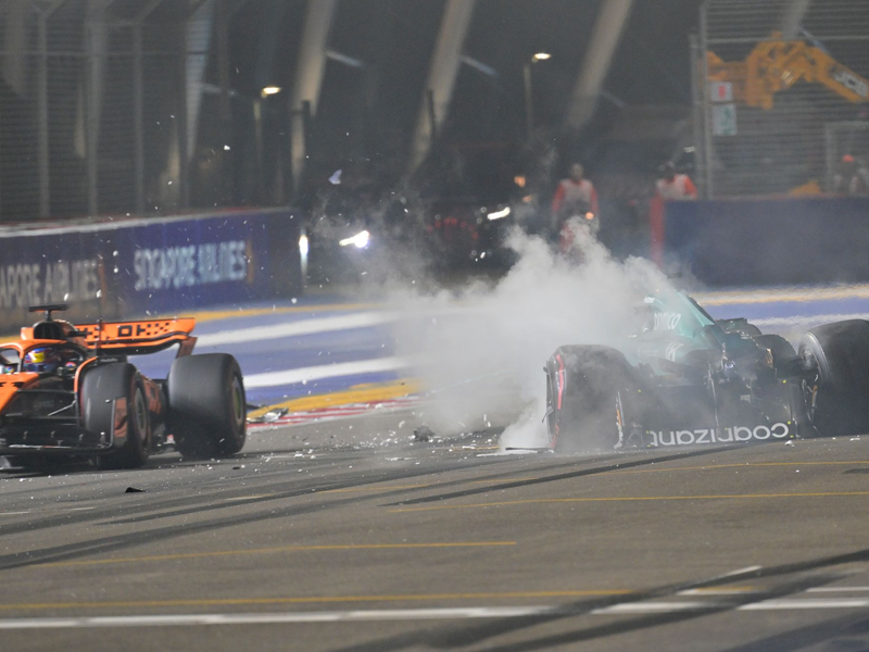 Nach einem Unfall steigt aus dem Auto von Lance Stroll (r) Rauch auf, während Oscar Piastri an der Unfallstelle vorbeifährt. - Foto: Caroline Chia/Reuters Pool/AP/dpa