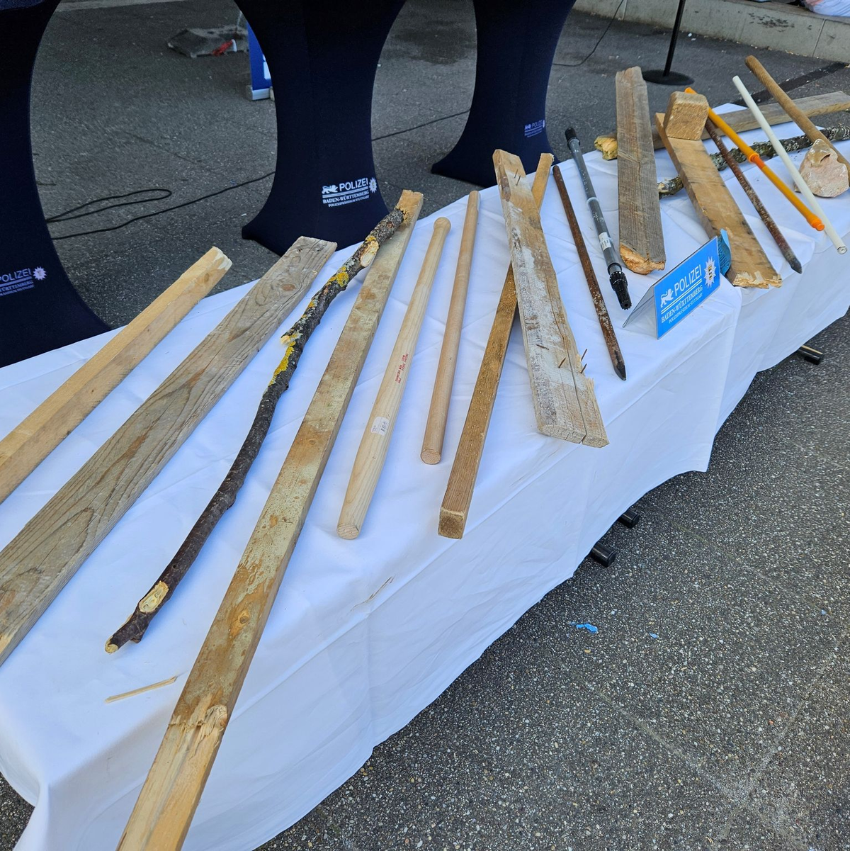 Von der Polizei gesichterte Stöcke und Latten liegen vor der Pressekonferenz zu den Ausschreitungen auf einem Tisch. - Foto: Andreas Rosar/dpa