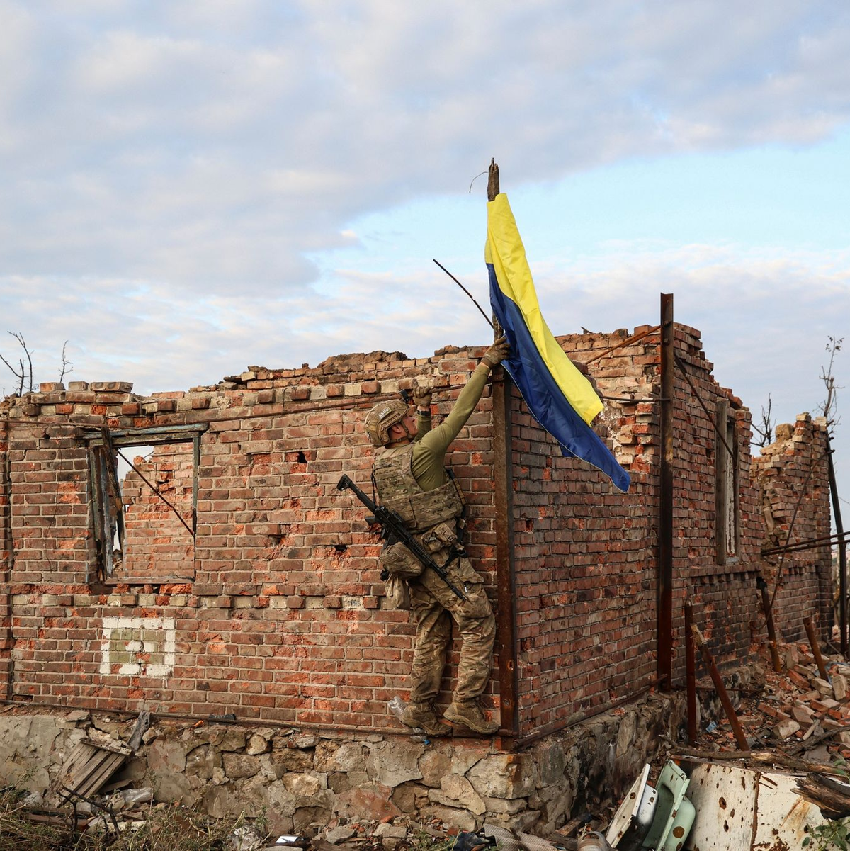 Ein ukrainischer Kommandeur hisst die Nationalflagge als Symbol der Befreiung des Frontdorfes Andrijewka in der Region Donezk. - Foto: Alex Babenko/AP/dpa