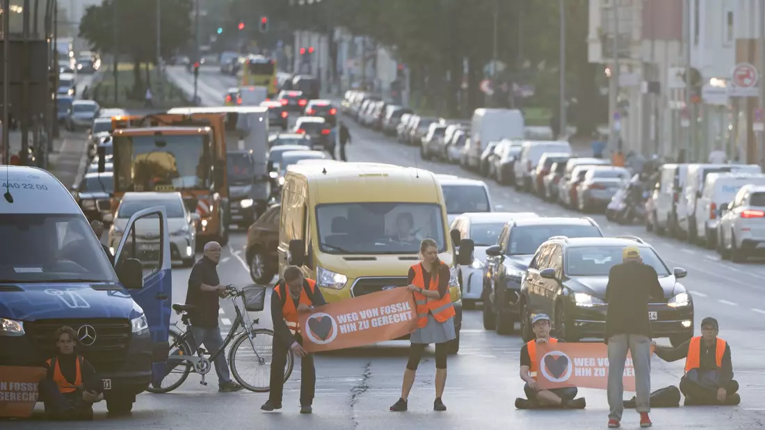 Statt sich auf die Straße zu setzen oder festzukleben, hielten Demonstrantinnen und Demonstranten heute ogenannte Laufblockaden ab und gingen mit Bannern vor dem Verkehr her. - Bild: Sebastian Christoph Gollnow/dpa