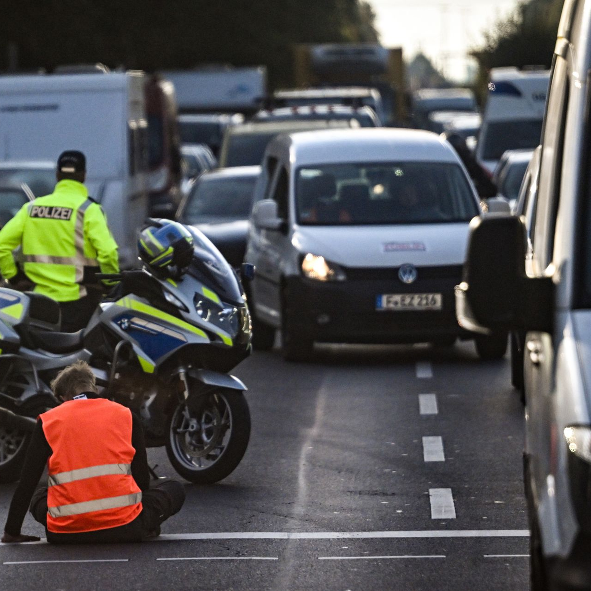Klima-Protest: Ein junger Mann hat sich auf der Köpenicker Landstraße in Berlin auf der Fahrbahn festgeklebt. - Foto: Britta Pedersen/dpa