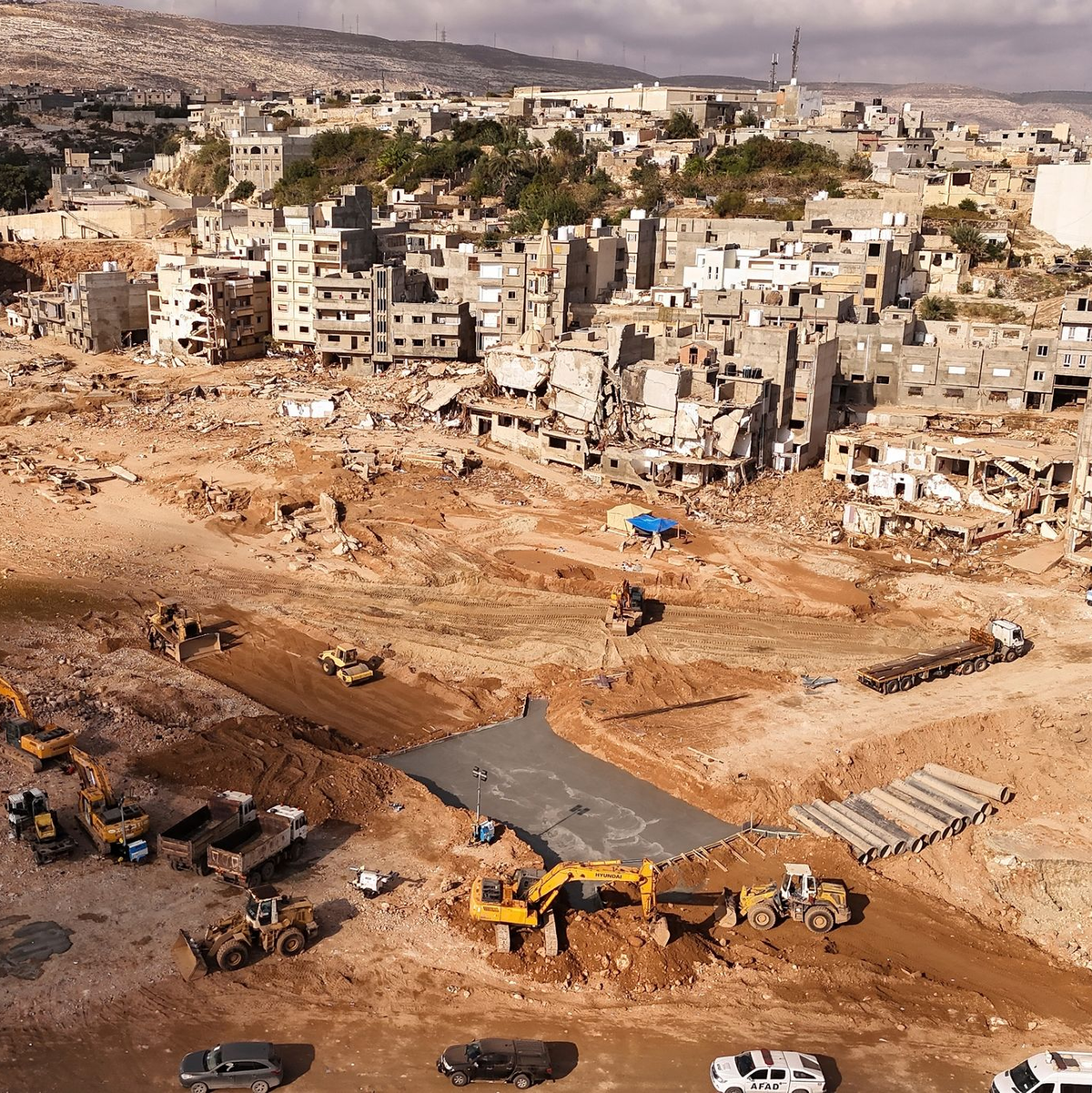 Bauarbeiter errichten eine Brücke zwischen dem östlichen und dem westlichen Teil von Darna, die durch den Dammbruch nach den jüngsten Überschwemmungen durch den Mittelmeersturm «Daniel» geteilt wurden. - Foto: Muhammad J. Elalwany/AP/dpa