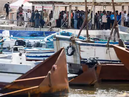 Migranten stehen an einem Hafen auf Lampedusa. - Foto: Cecilia Fabiano/LaPresse via ZUMA Press/dpa