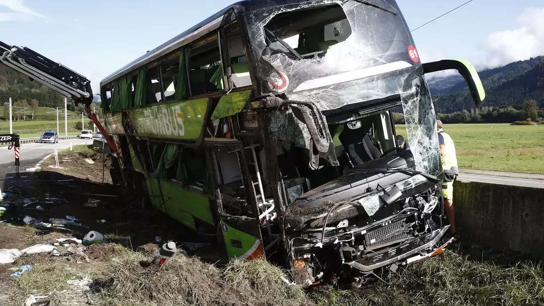 Der verunglückte Reisebus liegt im Graben: Bei dem Busunfall in Kärnten ist eine Frau ums Leben gekommen. - Bild: Gert Eggenberger/APA/dpa
