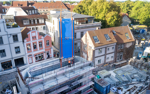 Ein tonnenschweres Scheibenteil wird von einem Kran in den Rohbau eines Aquariums manövriert. - Foto: Stefan Sauer/dpa