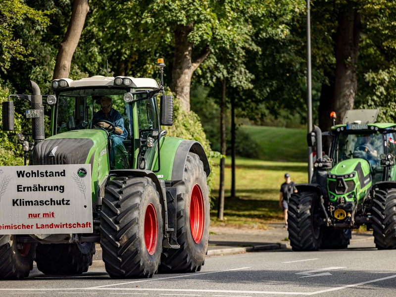 Ein Traktor mit einem Plakat mit der Aufschrift «Wohlstand Ernährung Klimaschutz nur mit heimischer Landwirtschaft» fährt zum Auftakt der Agrarministerkonferenz durch die Kieler Innenstadt. - Foto: Axel Heimken/dpa