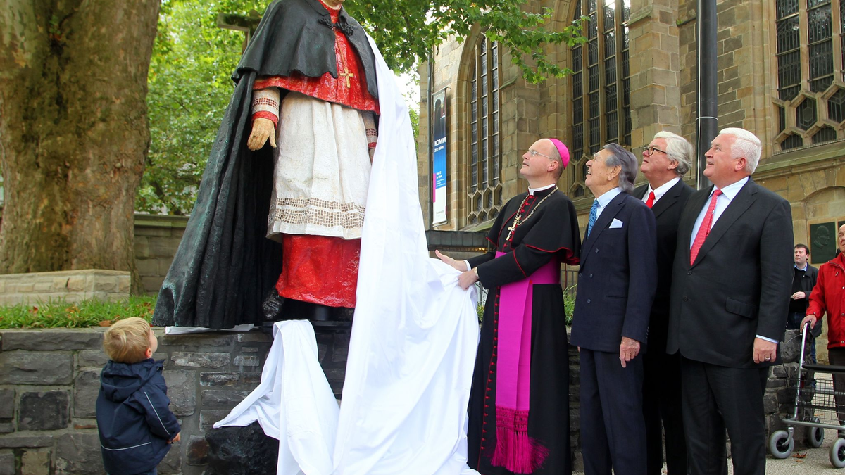 Franz-Josef Overbeck (l) enthüllt 2011 mit Gästen die Skulptur für den verstorbenen Franz Kardinal Hengsbach. - Foto: Roland Weihrauch/dpa