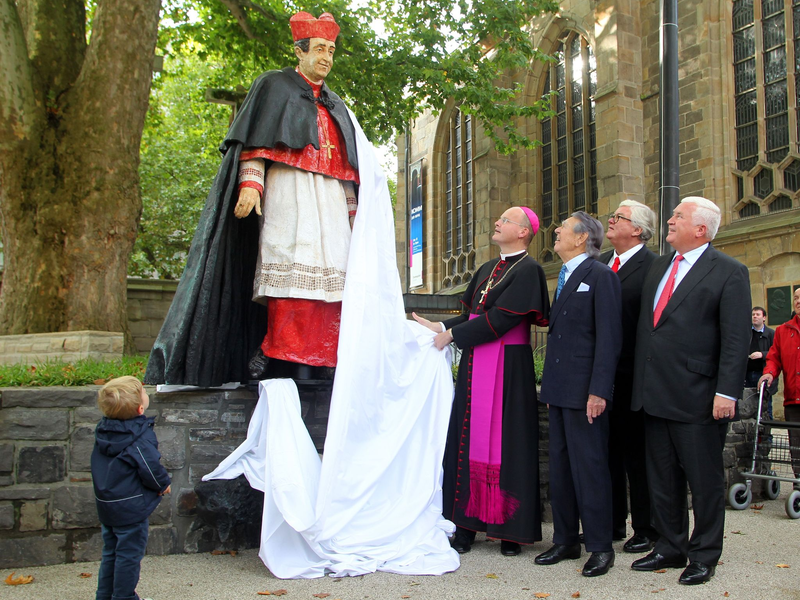 Franz-Josef Overbeck (l) enthüllt 2011 mit Gästen die Skulptur für den verstorbenen Franz Kardinal Hengsbach. - Foto: Roland Weihrauch/dpa
