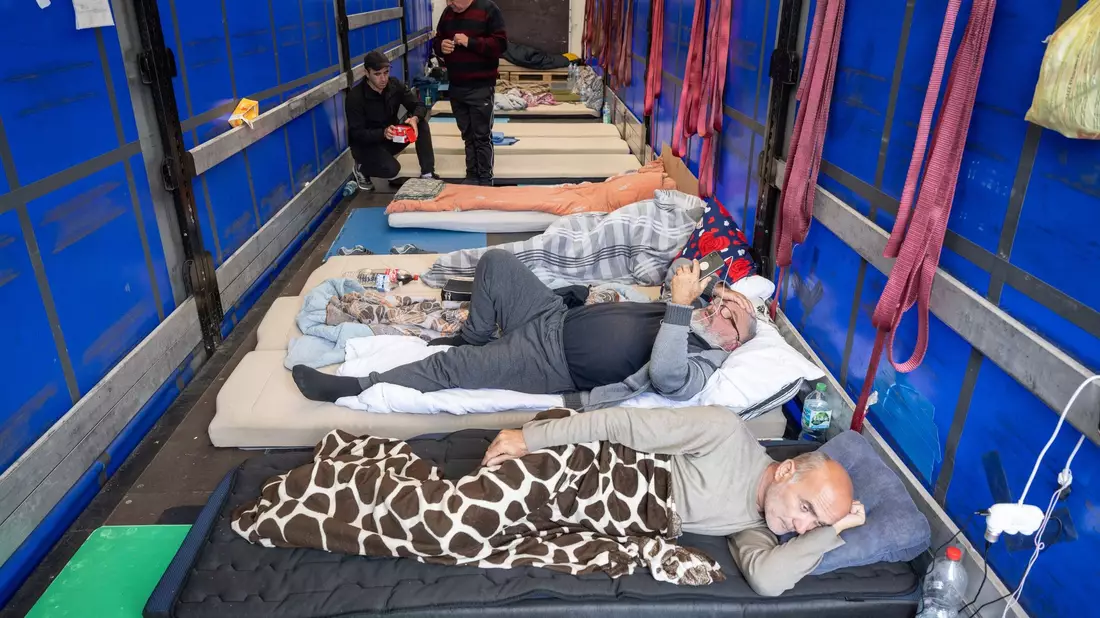 Trucker aus Georgien liegen auf einem Matratzenlager auf der Ladefläche eines Lkw. Sie sind in einen Hungerstreik getreten. - Bild: Boris Roessler/dpa
