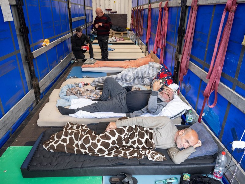 Trucker aus Georgien liegen auf einem Matratzenlager auf der Ladefläche eines Lkw. Sie sind in einen Hungerstreik getreten. - Foto: Boris Roessler/dpa