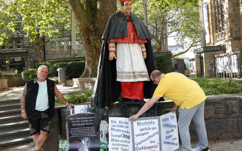 Nach Missbrauchsvorwürfen gegen den 1991 gestorbenen Essener Kardinal Hengsbach stellen die Betroffenenvertreter Markus Elstner (l) und Wilfried Fesselmann Protesttafeln auf. - Foto: Roland Weihrauch/dpa