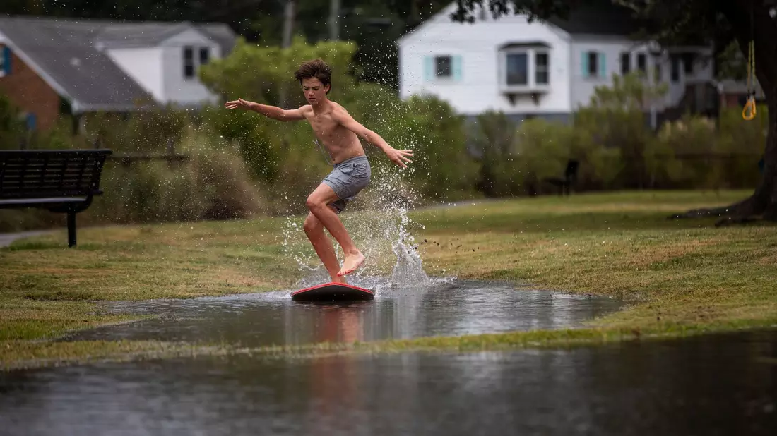 Ein Junge gleitet in Norfolk im US-Bundesstaat Virginia über das hohe Wasser des Lafayette River, während sich der Tropensturm «Ophelia» nähert. - Bild: Kendall Warner/The Virginian-Pilot/AP/dpa