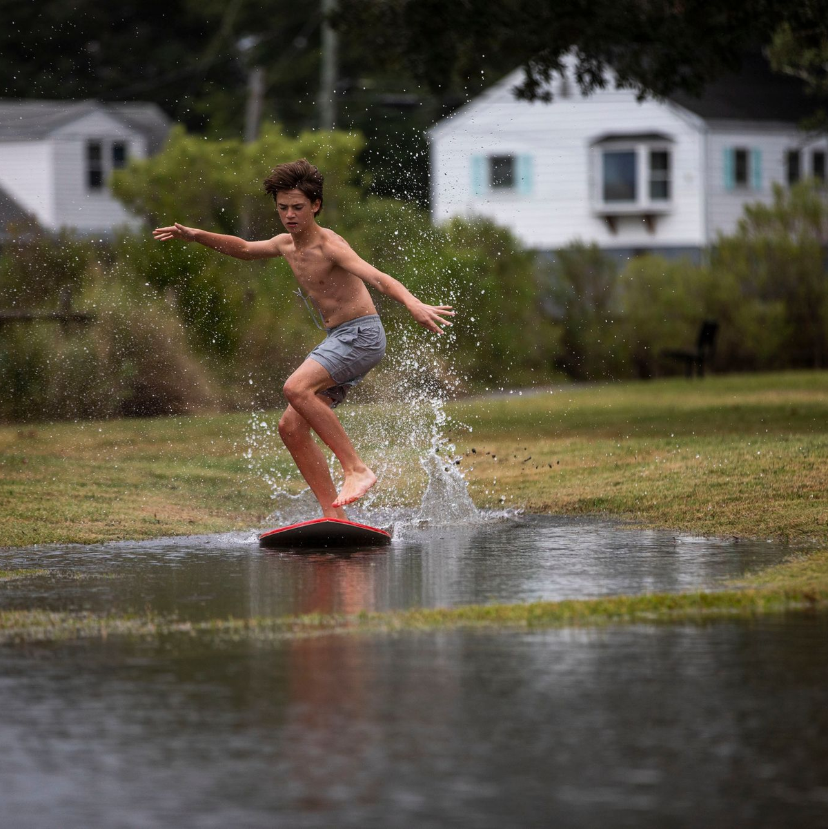 Ein Junge gleitet in Norfolk im US-Bundesstaat Virginia über das hohe Wasser des Lafayette River, während sich der Tropensturm «Ophelia» nähert. - Foto: Kendall Warner/The Virginian-Pilot/AP/dpa