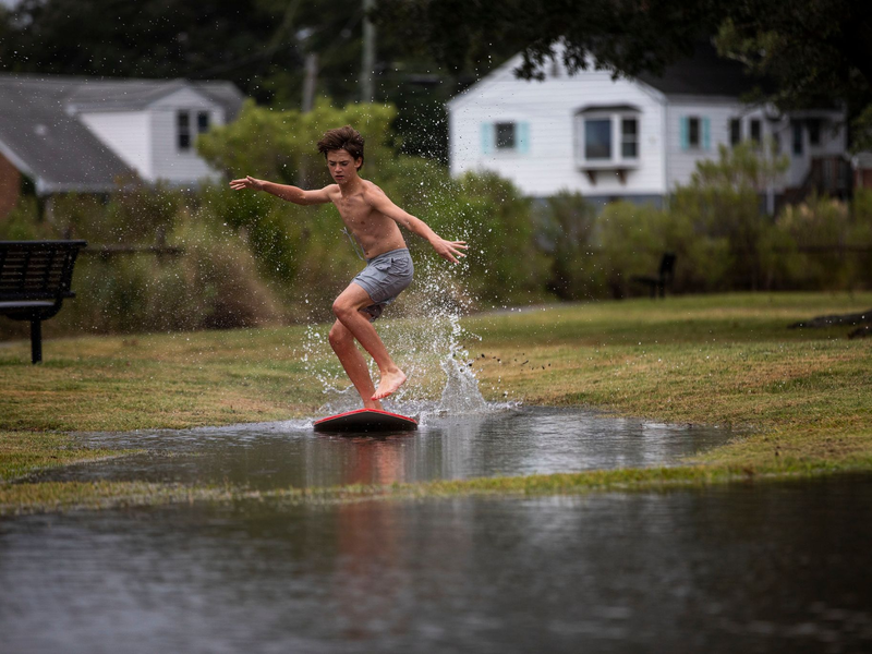 Ein Junge gleitet in Norfolk im US-Bundesstaat Virginia über das hohe Wasser des Lafayette River, während sich der Tropensturm «Ophelia» nähert. - Foto: Kendall Warner/The Virginian-Pilot/AP/dpa
