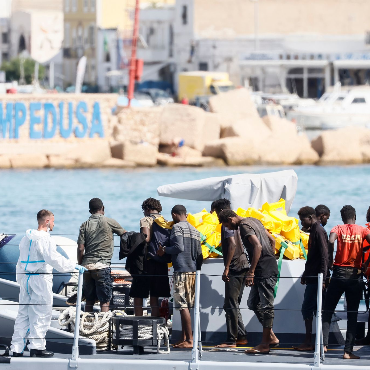 Gerettete Migranten stehen auf einem Boot der italienischen Behörden, bevor sie im Hafen der süditalienischen Insel Lampedusa von Bord gehen. - Foto: Cecilia Fabiano/LaPresse/AP/dpa