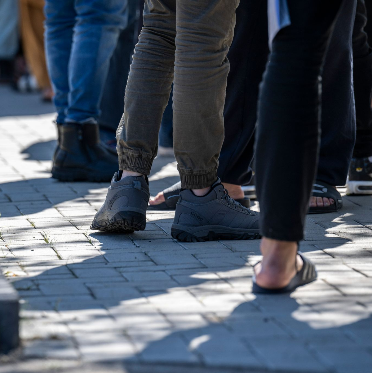 Asylbewerber stehen in einer Erstaufnahme-Einrichtung in Brandenburg in einer Schlange. - Foto: Hannes P Albert/dpa