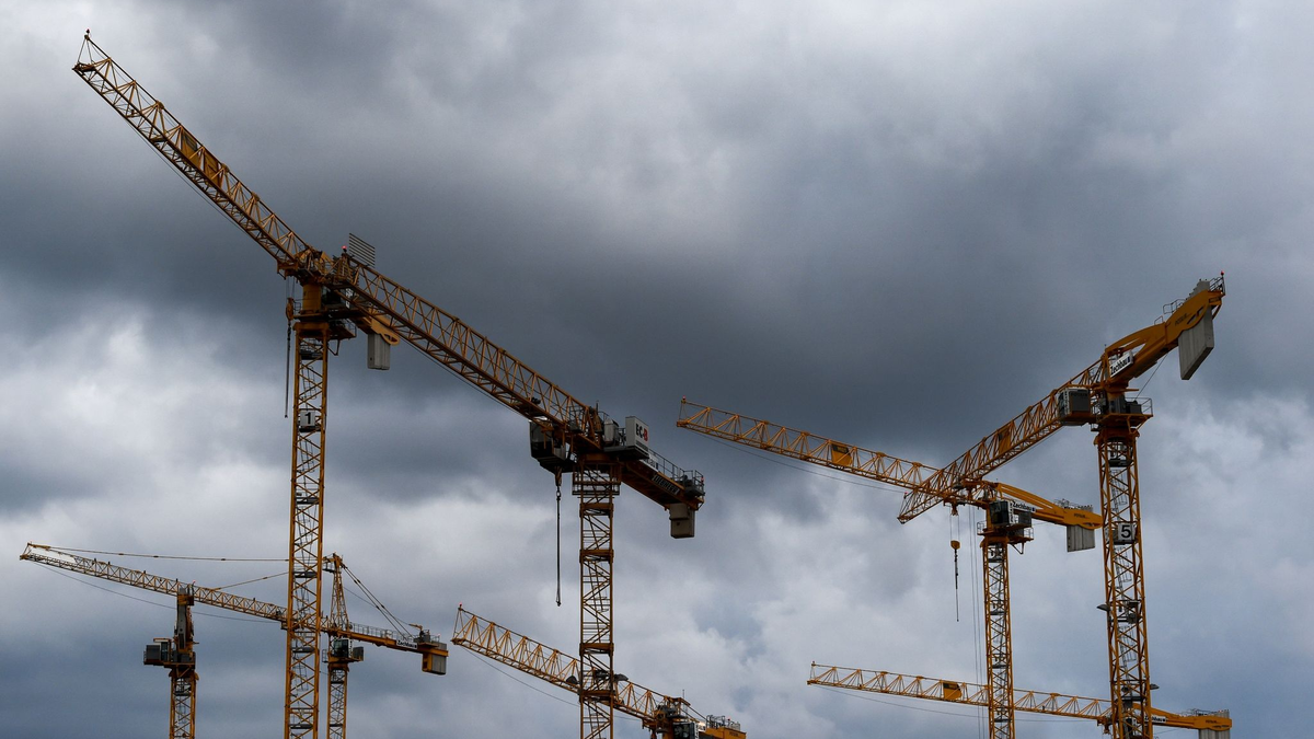 Dunkle Wolken ziehen über die Kräne auf einer Baustelle. «Alle Indikatoren am Bau zeigen deutlich nach unten, eine Trendwende ist nicht in Sicht», stellt die Bauindustrie fest. - Foto: Lisa Ducret/dpa