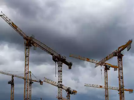 Dunkle Wolken ziehen über die Kräne auf einer Baustelle. «Alle Indikatoren am Bau zeigen deutlich nach unten, eine Trendwende ist nicht in Sicht», stellt die Bauindustrie fest. - Foto: Lisa Ducret/dpa