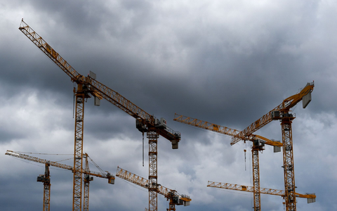 Dunkle Wolken ziehen über die Kräne auf einer Baustelle. «Alle Indikatoren am Bau zeigen deutlich nach unten, eine Trendwende ist nicht in Sicht», stellt die Bauindustrie fest. - Foto: Lisa Ducret/dpa