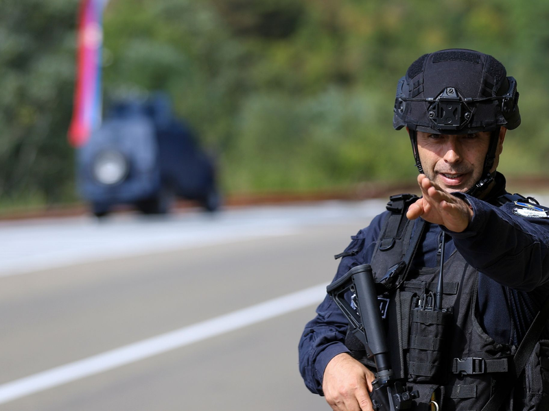 Ein Kosovo-Polizist bewacht eine Straße in der Nähe des Dorfes Banjska. Maskierte Angreifer haben im Norden des Kosovos einen Polizisten erschossen. - Foto: Bojan Slavkovic/AP/dpa