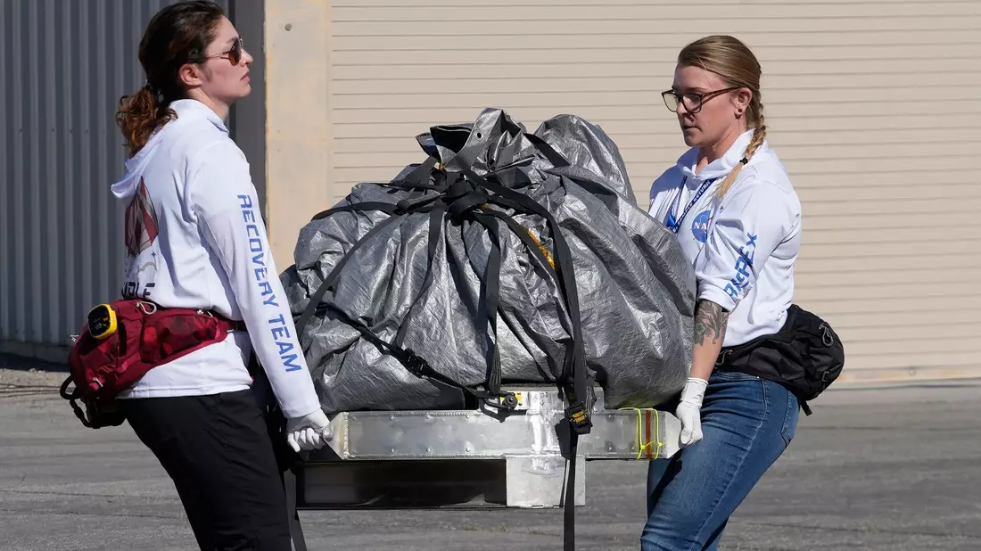 Mitglieder des Nasa-Bergungsteams transportieren die Kapsel mit den Asteroidenproben in ein steriles Labor nahe der Landestelle. - Bild: Rick Bowmer/AP Pool/dpa