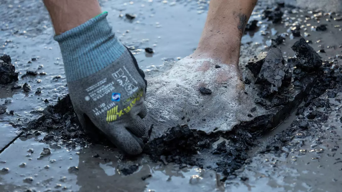 Ein Polizist entfernt Asphalt, um einen Aktivisten von der Straße zu lösen. - Bild: Hannes P. Albert/dpa