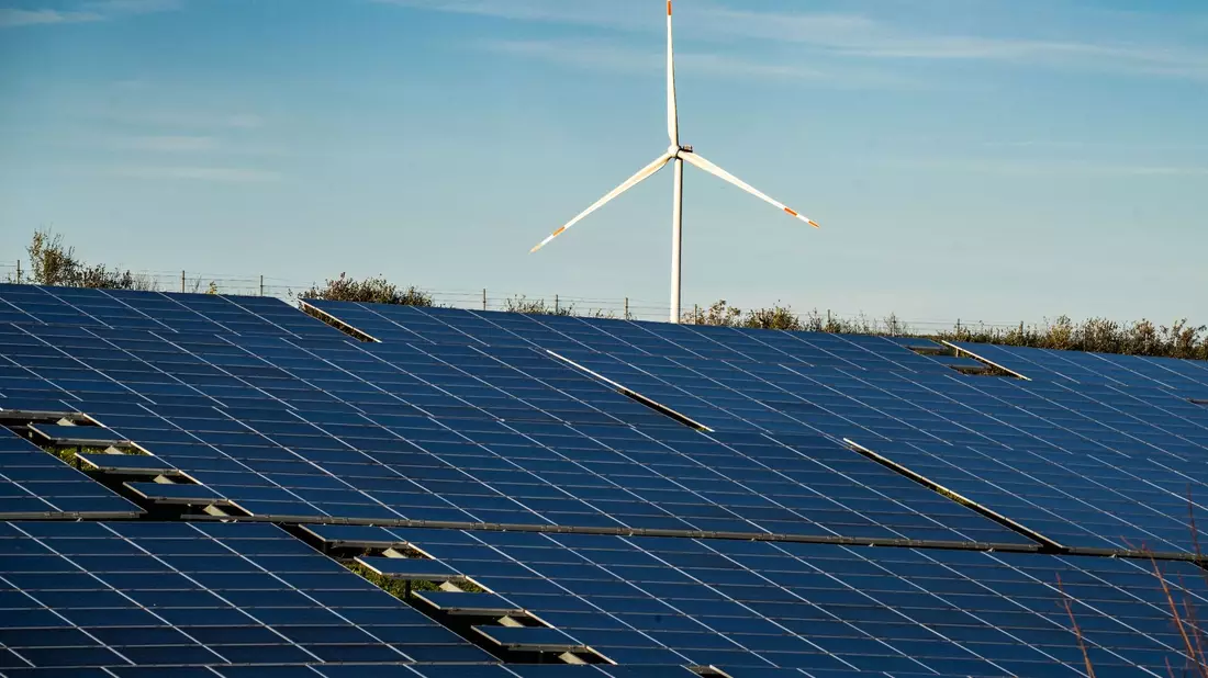 Ein Windrad steht auf einem Hügel einer großflächigen Solaranlage. - Bild: Frank Rumpenhorst/dpa