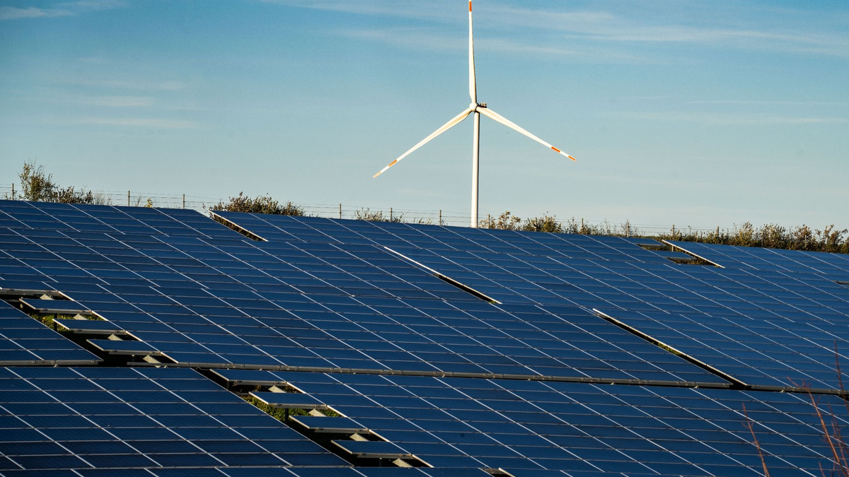 Ein Windrad steht auf einem Hügel einer großflächigen Solaranlage. - Foto: Frank Rumpenhorst/dpa