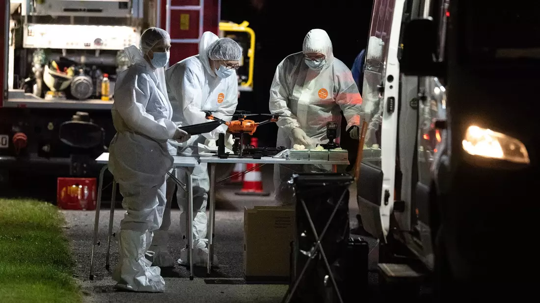 Mitarbeiter der Spurensicherung stehen nach dem Fund einer Frauenleiche an ihren Einsatzfahrzeugen. - Bild: Swen Pförtner/dpa