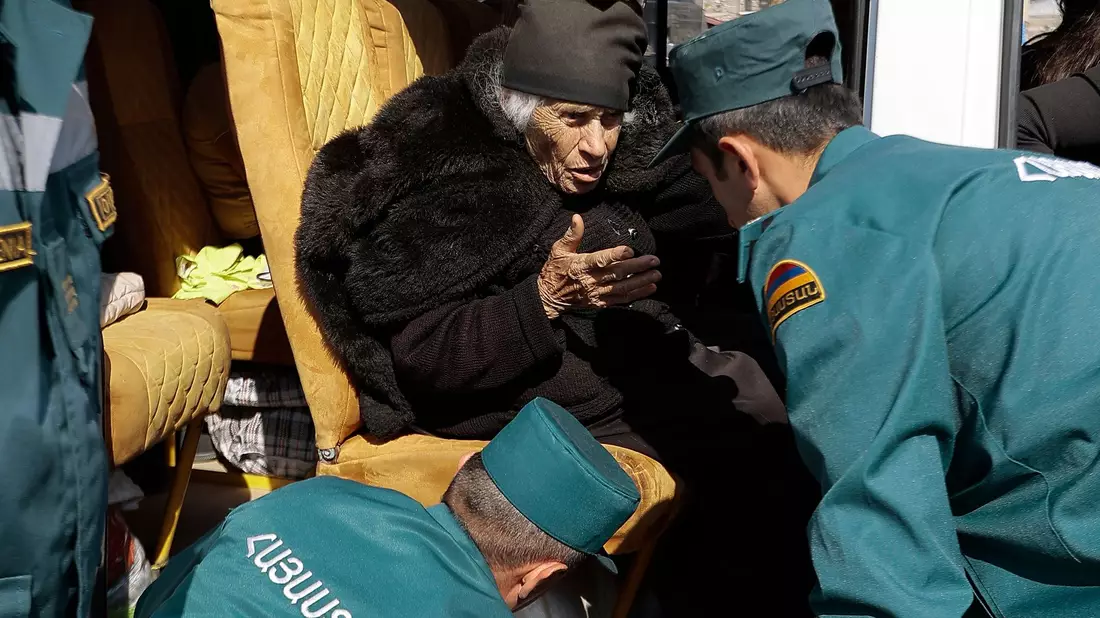 Mitarbeiter des armenischen Ministeriums für Notfallsituationen sprechen mit einer älteren armenischen Frau aus Berg-Karabach bei ihrer Ankunf in Goris. - Bild: Vasily Krestyaninov/AP/dpa