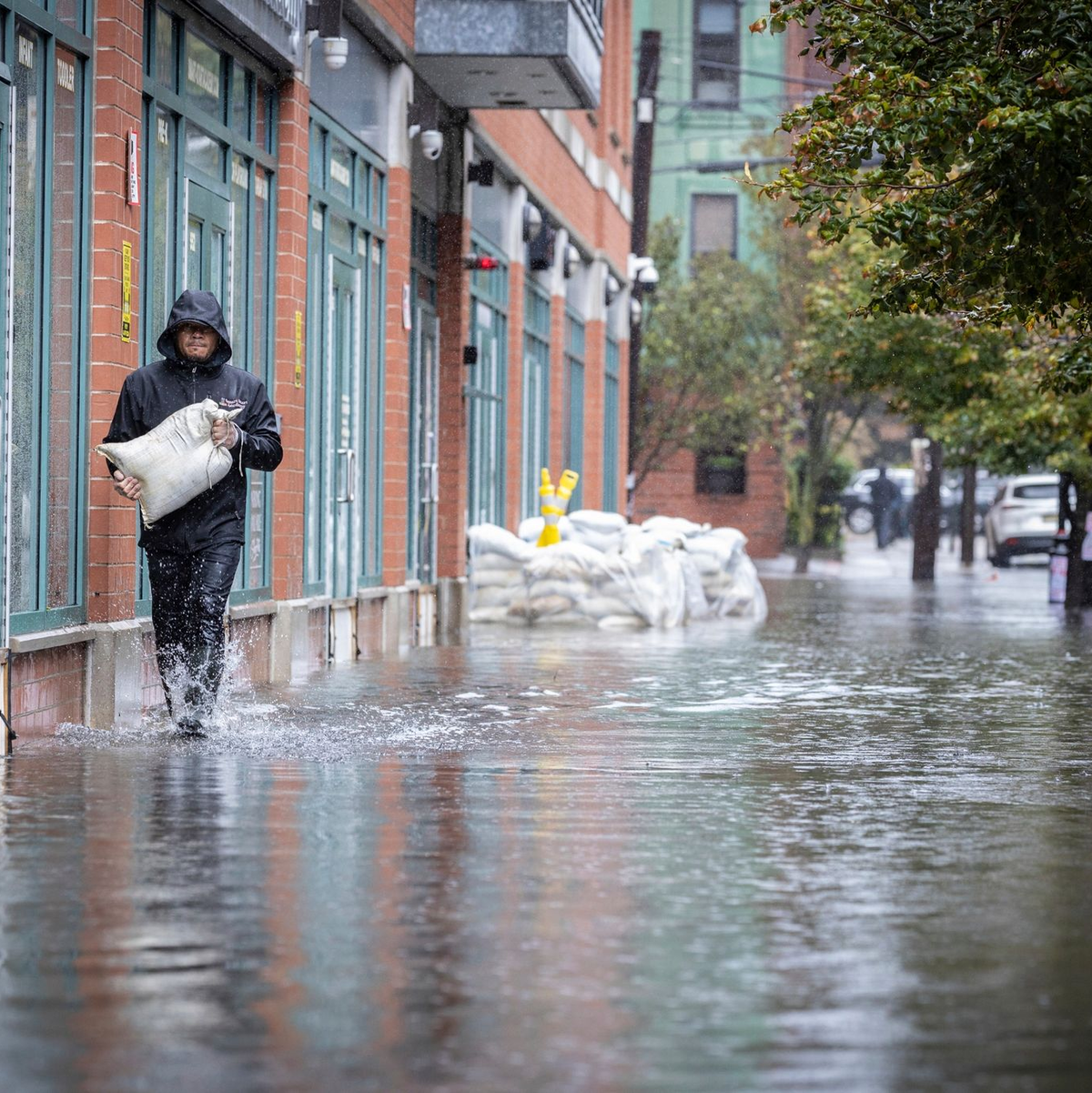 Mit Sandsäcken versucht ein Mann zu verhindern, dass Wasser in ein Gebäude eindringt. - Foto: Stefan Jeremiah/AP/dpa