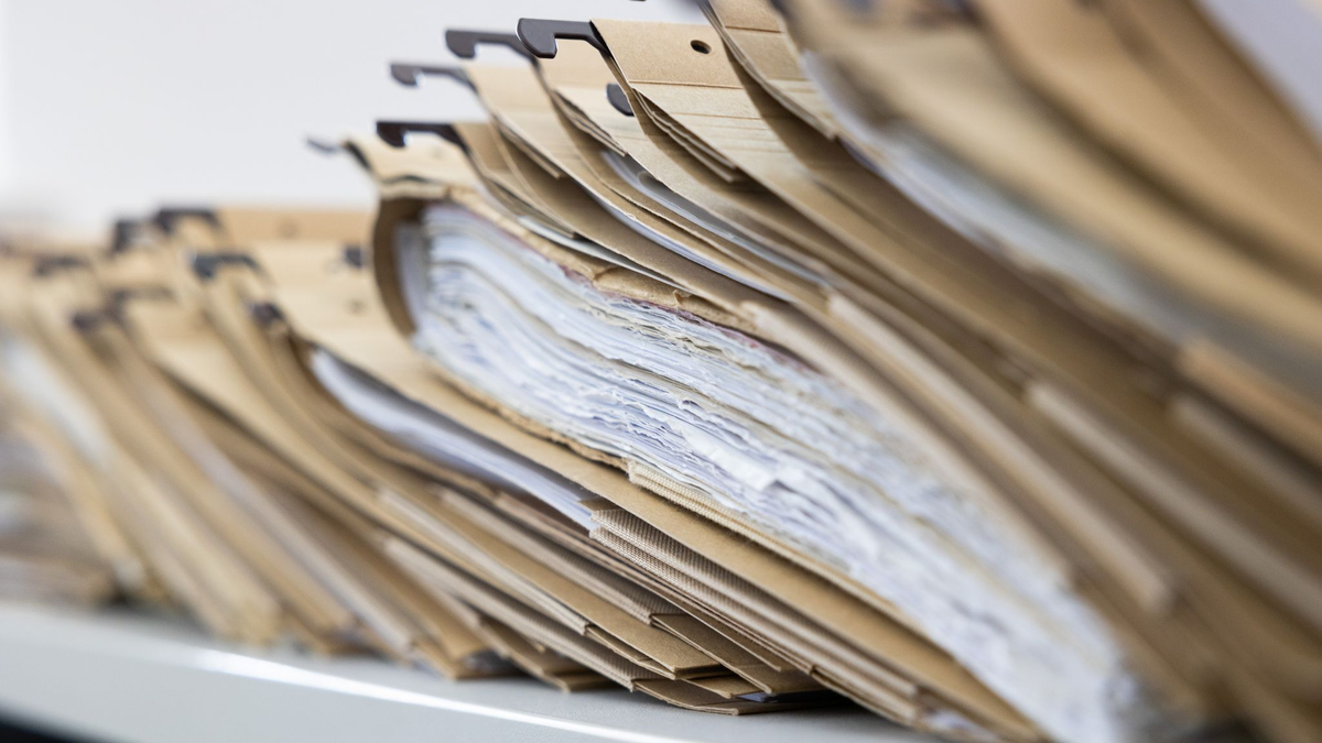 Zahlreiche Akten sind auf einem Schreibtisch ausgelegt. - Foto: Lando Hass/dpa